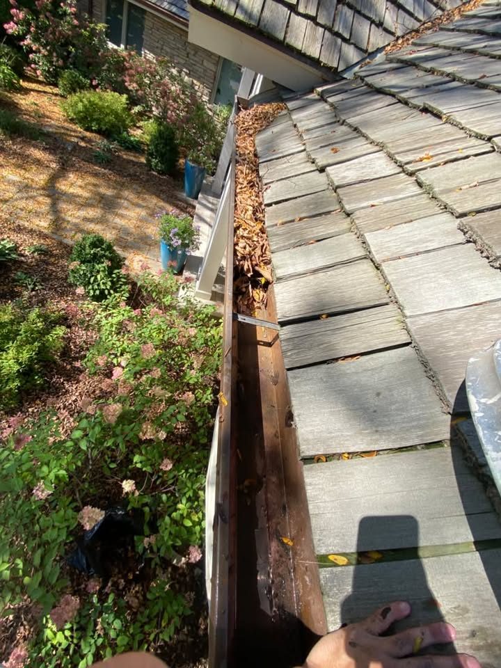Gutter half cleared by hand with dry leaves still packed at the far end, gutter cleaning in Libertyville, IL