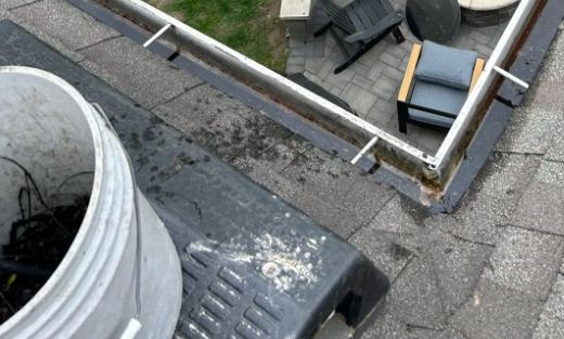 View from the roof edge along a gutter line above a back patio, gutter cleaning in Lake County, IL