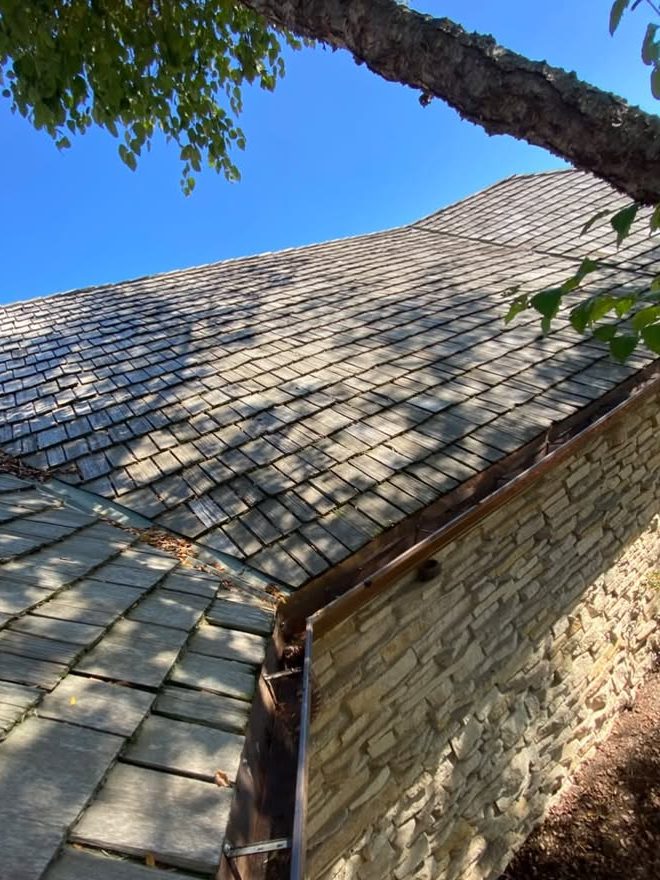 Leaves caught where two roof sections meet above a gutter corner, gutter cleaning in Deerfield, IL